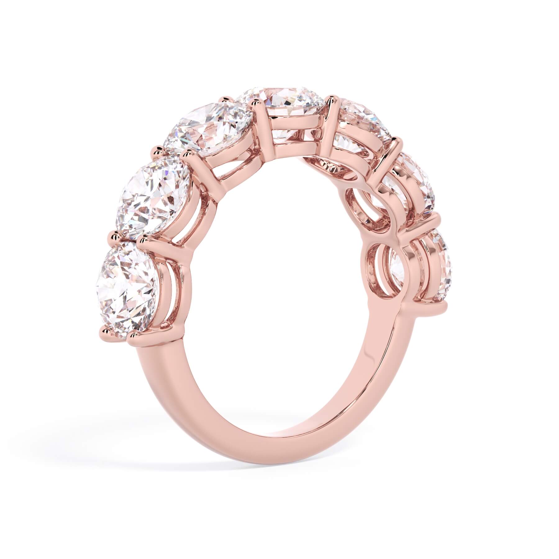 A picture of a seven stone diamond wedding ring with round diamonds that are shared prong set in rose gold on a white background with a slightly angled, through the finger view.
