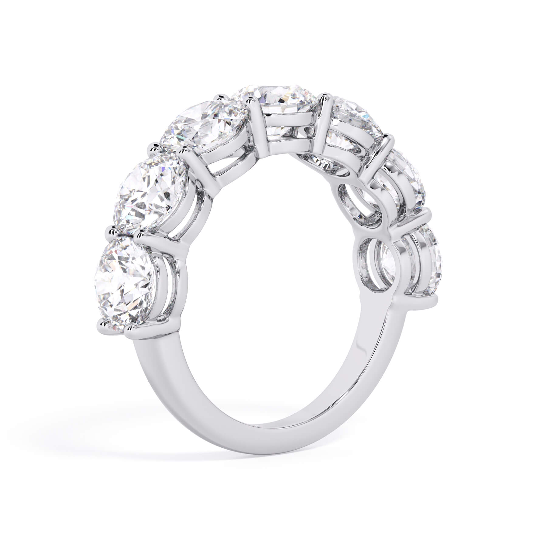 A picture of a seven stone diamond wedding ring with round diamonds that are shared prong set in white gold or platinum on a white background with a slightly angled, through the finger view.