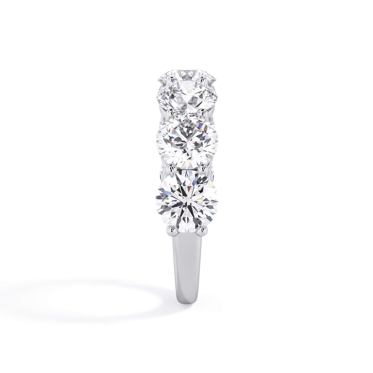 A picture of a seven stone diamond wedding ring with round diamonds that are shared prong set in white gold or platinum on a white background with a side profile view.