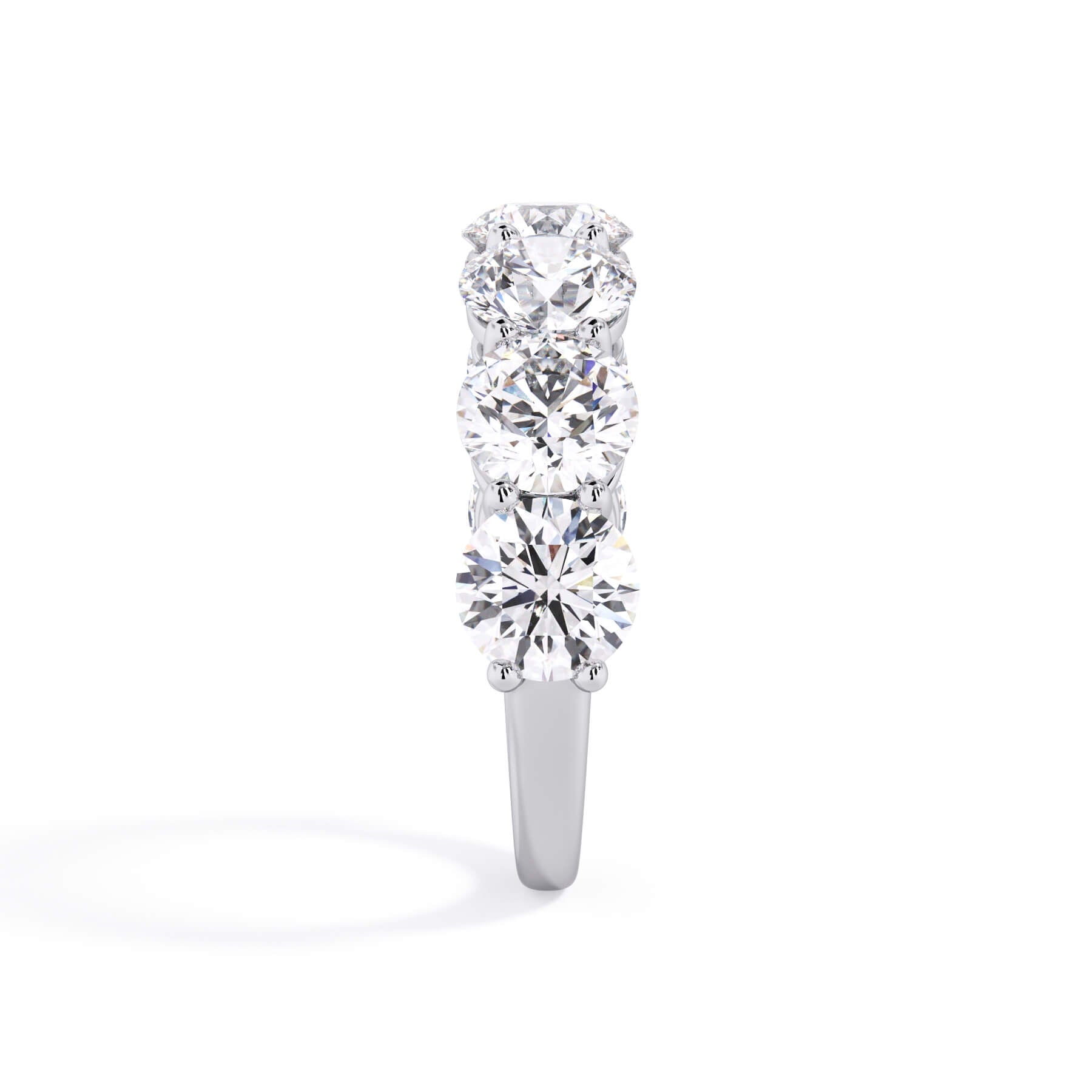 A picture of a seven stone diamond wedding ring with round diamonds that are shared prong set in white gold or platinum on a white background with a side profile view.