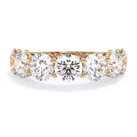 A picture of a seven stone diamond wedding ring with round diamonds that are shared prong set in yellow gold on a white background with the ring facing forward, lying down.