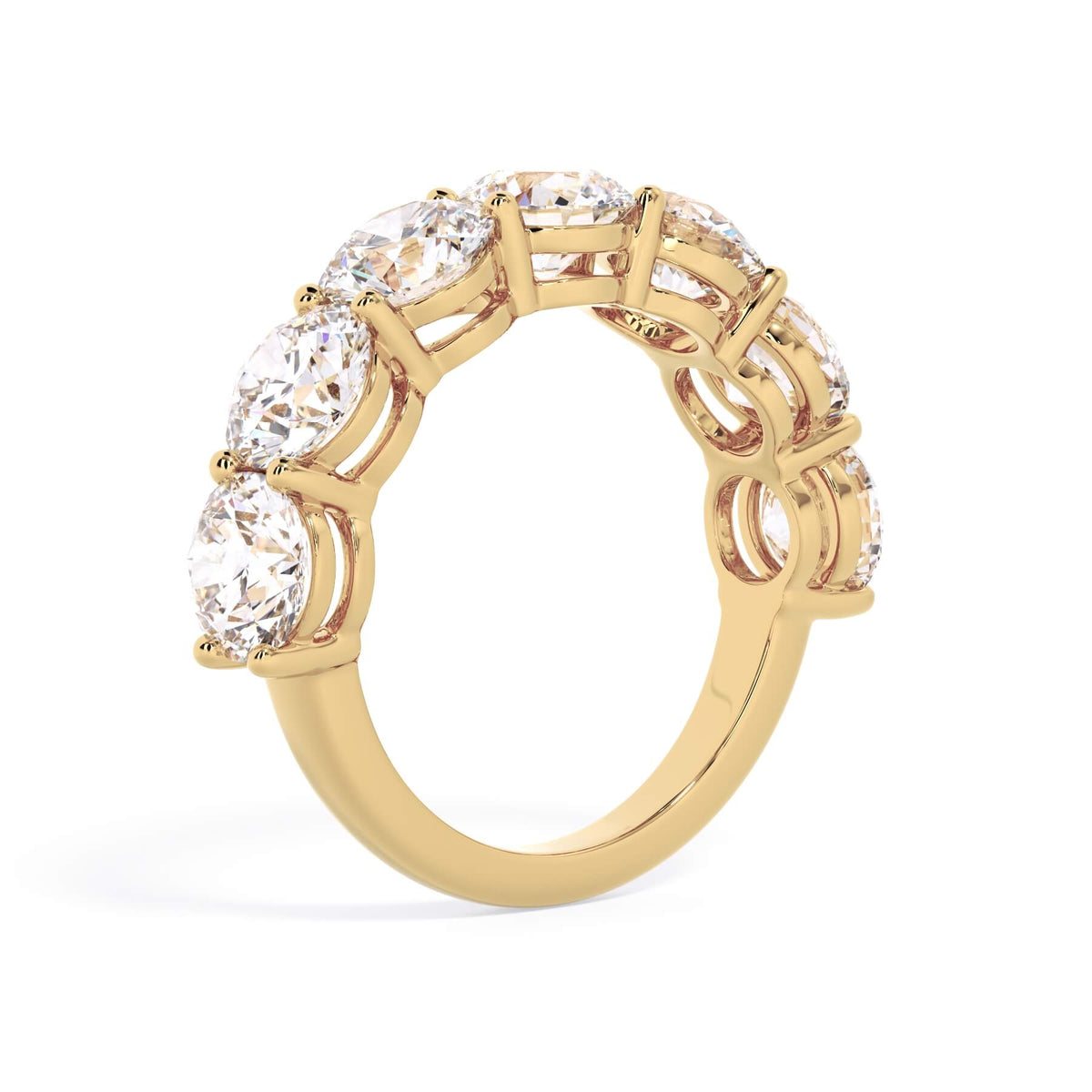 A picture of a seven stone diamond wedding ring with round diamonds that are shared prong set in yellow gold on a white background with a slightly angled, through the finger view.