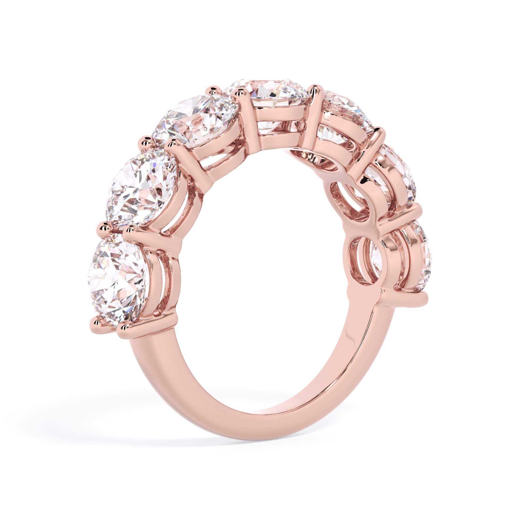 A picture of a seven stone diamond wedding ring with round diamonds that are shared prong set in rose gold on a white background with a slightly angled, through the finger view.