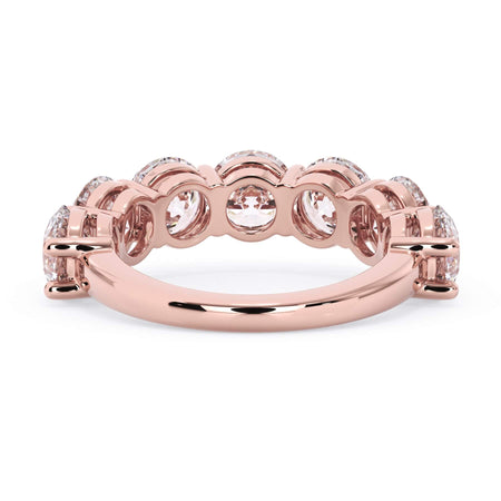 A picture of a seven stone diamond wedding ring with round diamonds that are shared prong set in rose gold on a white background with a view of the underside of the ring.