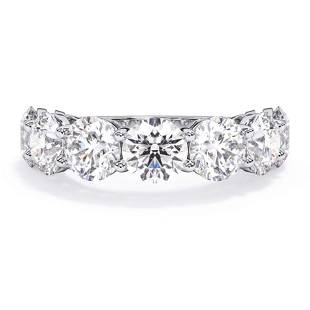 A picture of a seven stone diamond wedding ring with round diamonds that are shared prong set in white gold or platinum on a white background with the ring facing forward, lying down.