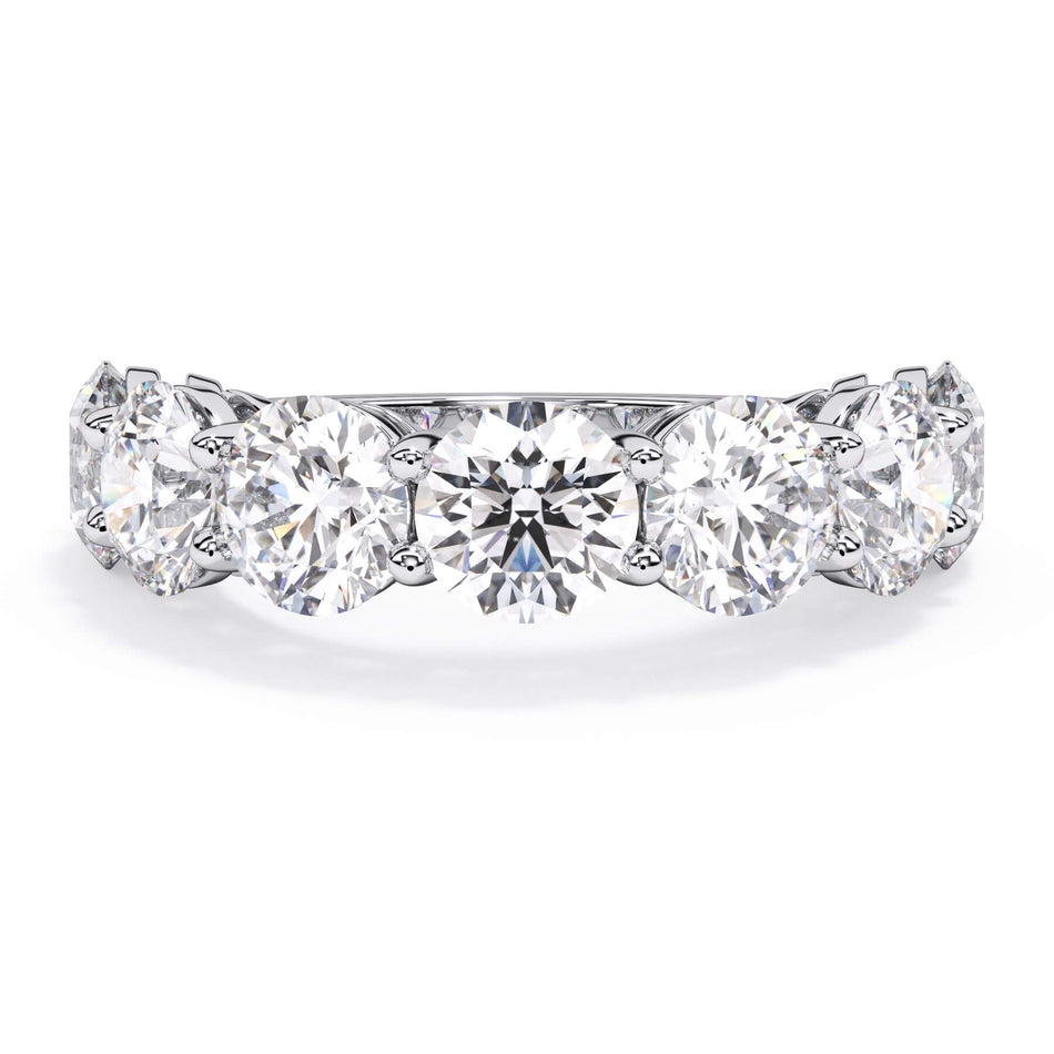 A picture of a seven stone diamond wedding ring with round diamonds that are shared prong set in white gold or platinum on a white background with the ring facing forward, lying down.