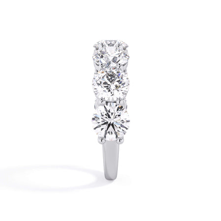 A picture of a seven stone diamond wedding ring with round diamonds that are shared prong set in white gold or platinum on a white background with a side profile view.