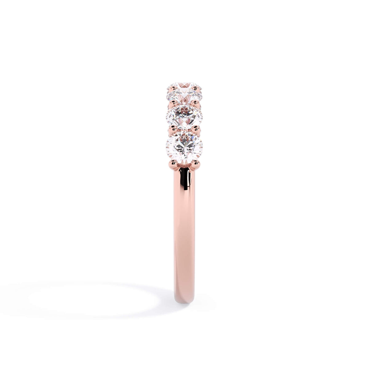 A picture of a seven stone diamond wedding ring with round diamonds that are U prong set in rose gold on a white background with a side profile view.
