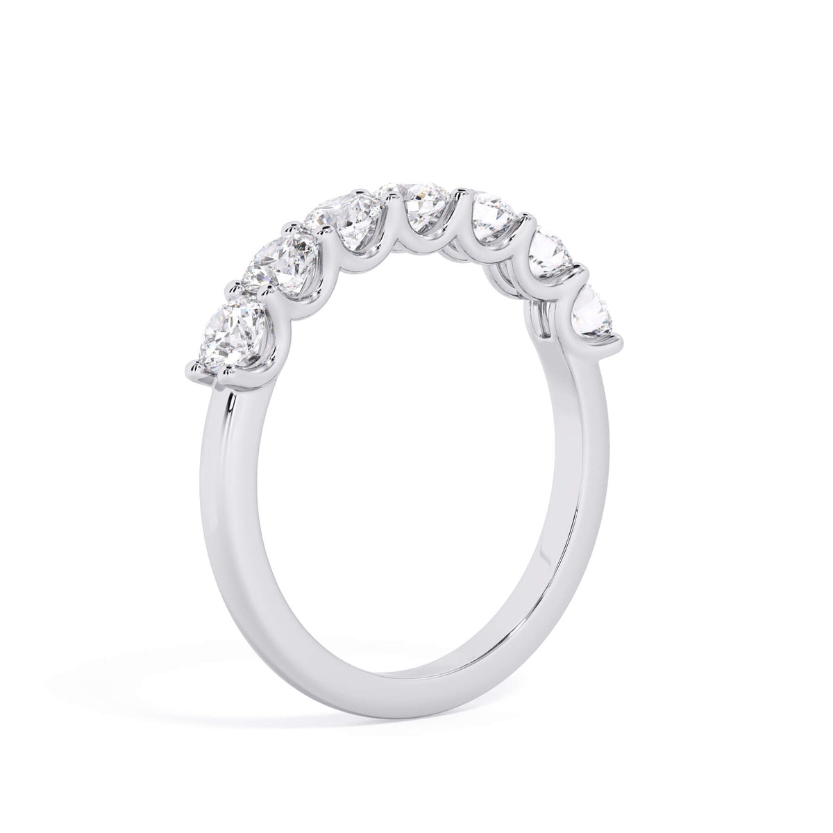 A picture of a seven stone diamond wedding ring with round diamonds that are U prong set in white gold or platinum on a white background with a slightly angled, through the finger view.