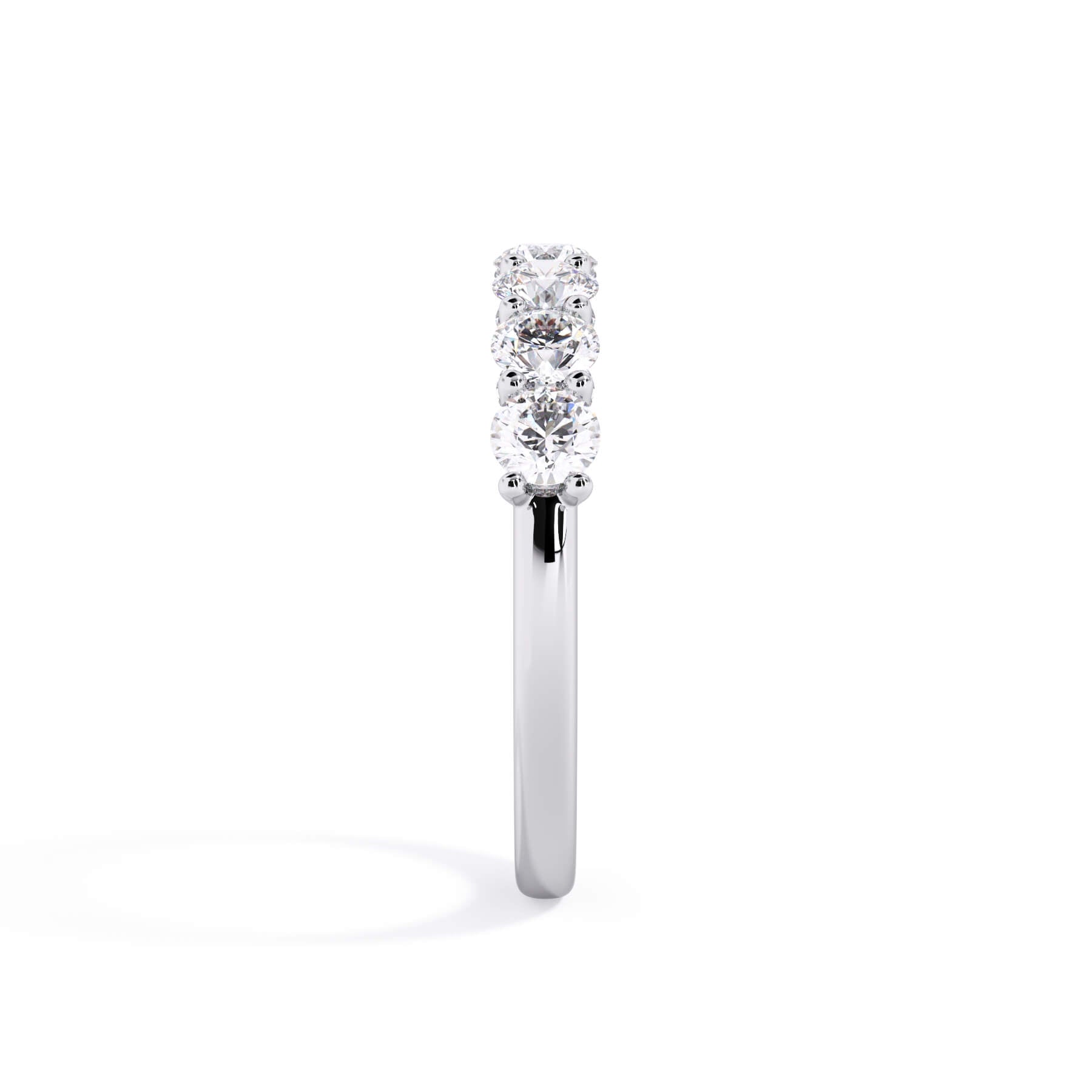 A picture of a seven stone diamond wedding ring with round diamonds that are U prong set in white gold or platinum on a white background with a side profile view.