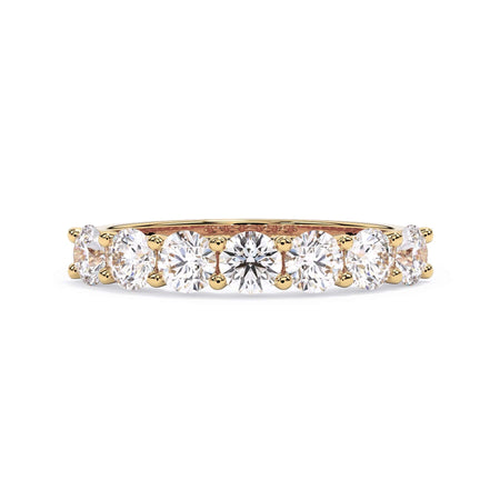 A picture of a seven stone diamond wedding ring with round diamonds that are U prong set in yellow gold on a white background with the ring facing forward, lying down.