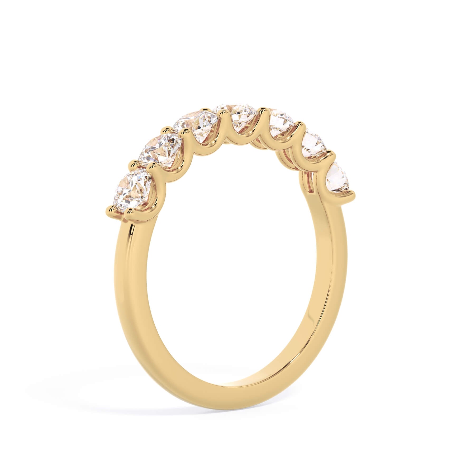 A picture of a seven stone diamond wedding ring with round diamonds that are U prong set in yellow gold on a white background with a slightly angled, through the finger view.
