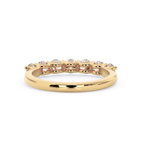 A picture of a seven stone diamond wedding ring with round diamonds that are U prong set in yellow gold on a white background with a view of the underside of the ring.