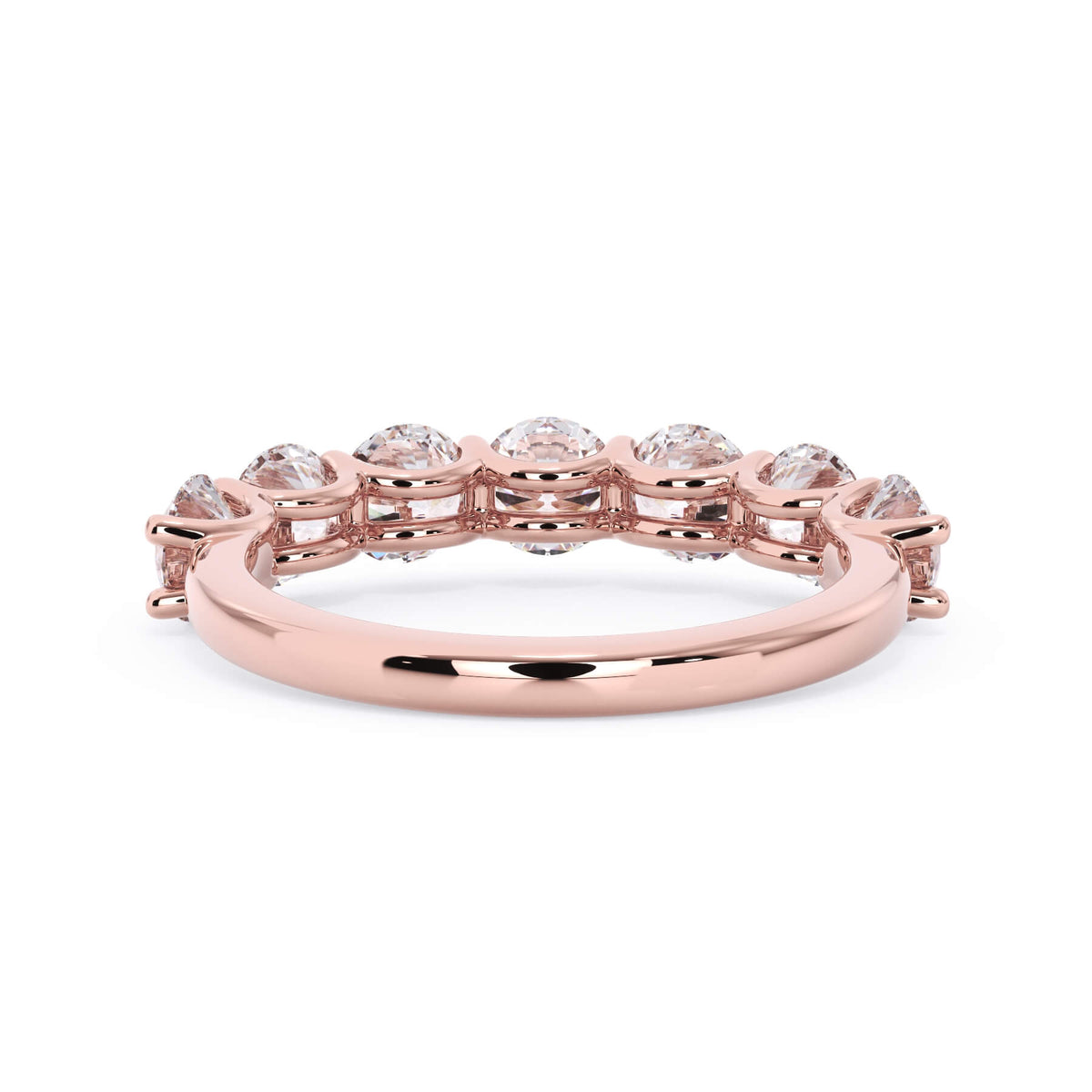 A picture of a seven stone diamond wedding ring with round diamonds that are U prong set in rose gold on a white background with a view of the underside of the ring.