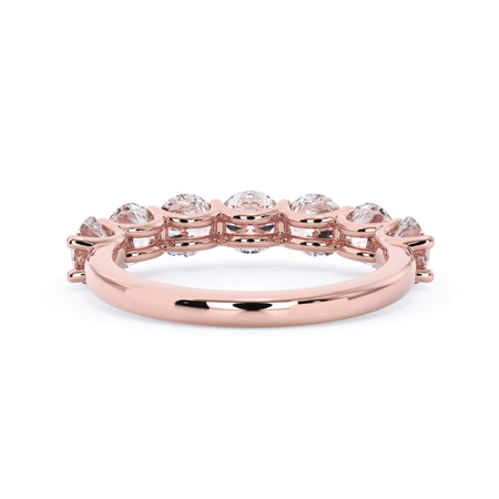 A picture of a seven stone diamond wedding ring with round diamonds that are U prong set in rose gold on a white background with a view of the underside of the ring.