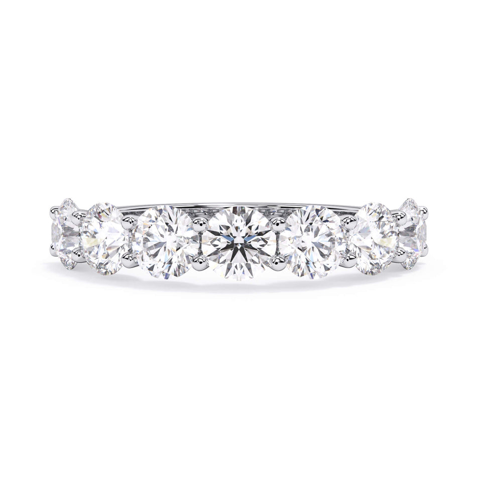 A picture of a seven stone diamond wedding ring with round diamonds that are U prong set in white gold or platinum on a white background with the ring facing forward, lying down.