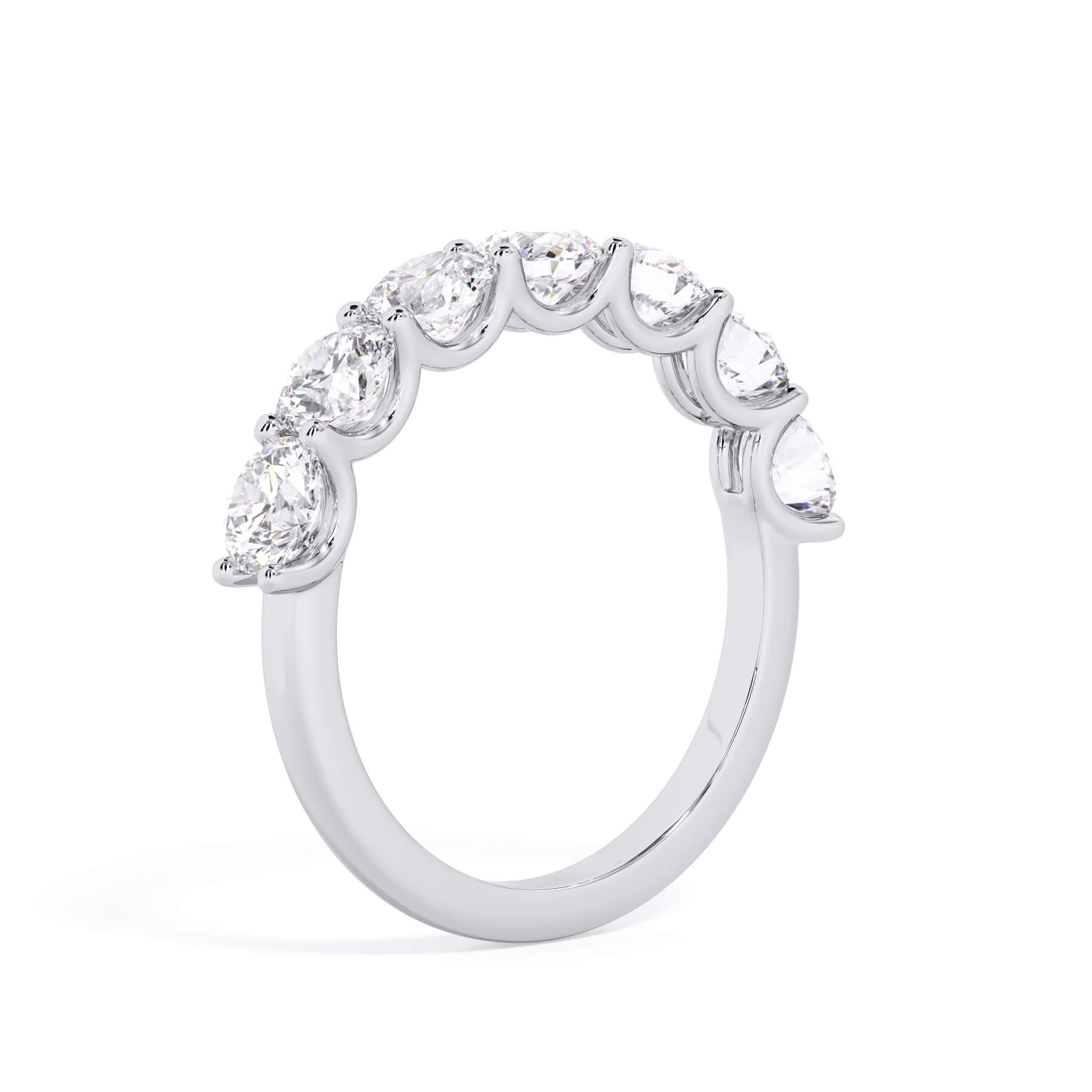 A picture of a seven stone diamond wedding ring with round diamonds that are U prong set in white gold or platinum on a white background with a slightly angled, through the finger view.