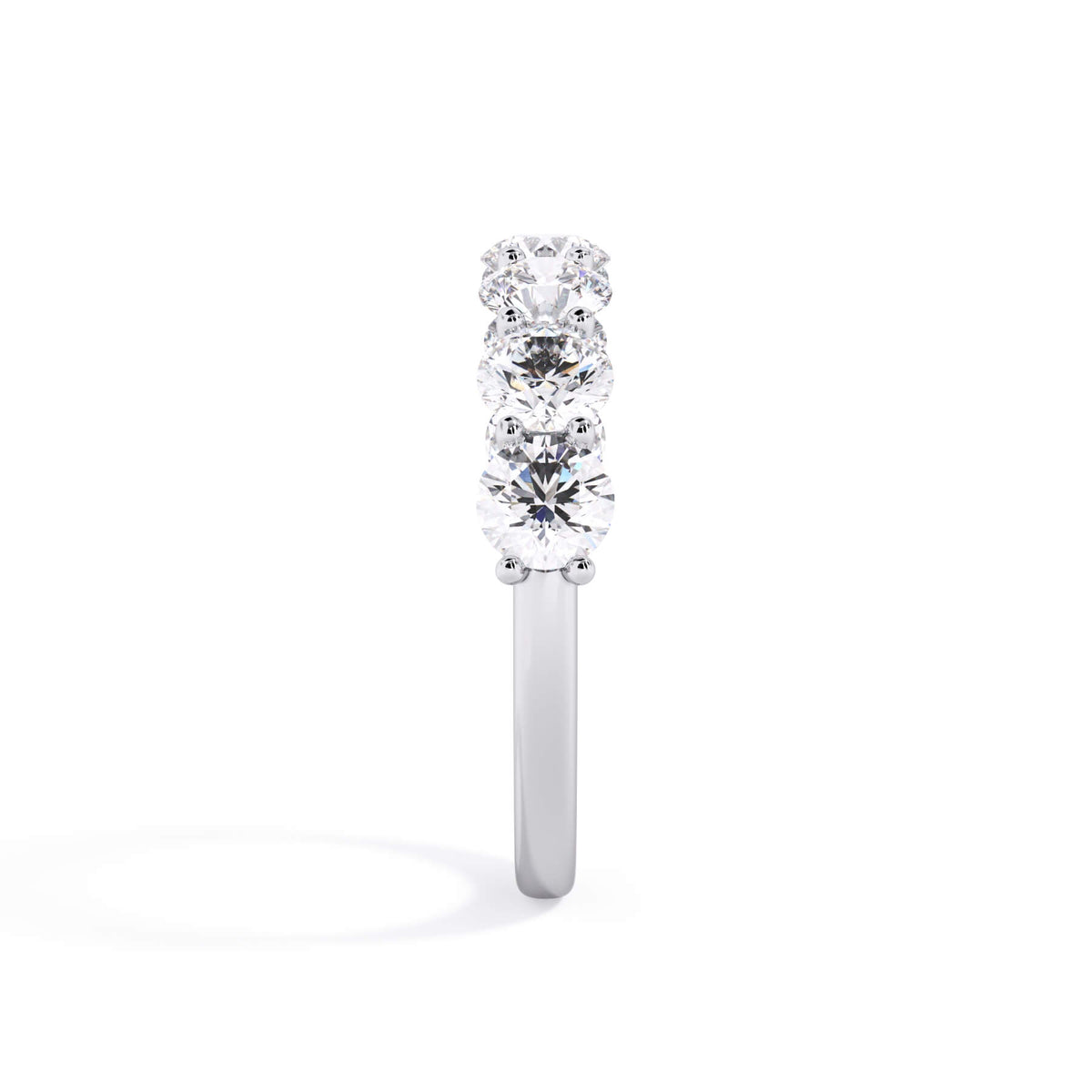 A picture of a seven stone diamond wedding ring with round diamonds that are U prong set in white gold or platinum on a white background with a side profile view.