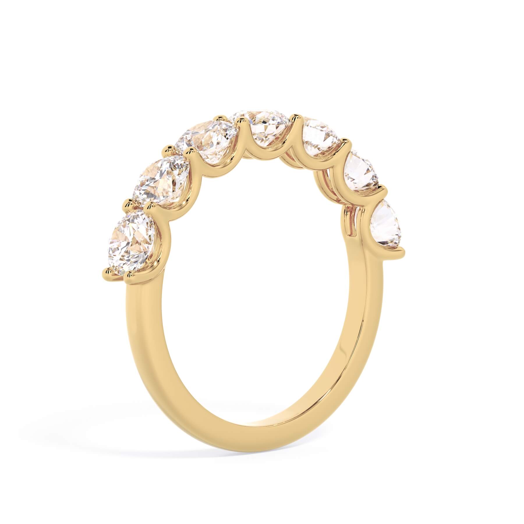 A picture of a seven stone diamond wedding ring with round diamonds that are U prong set in yellow gold on a white background with a slightly angled, through the finger view.
