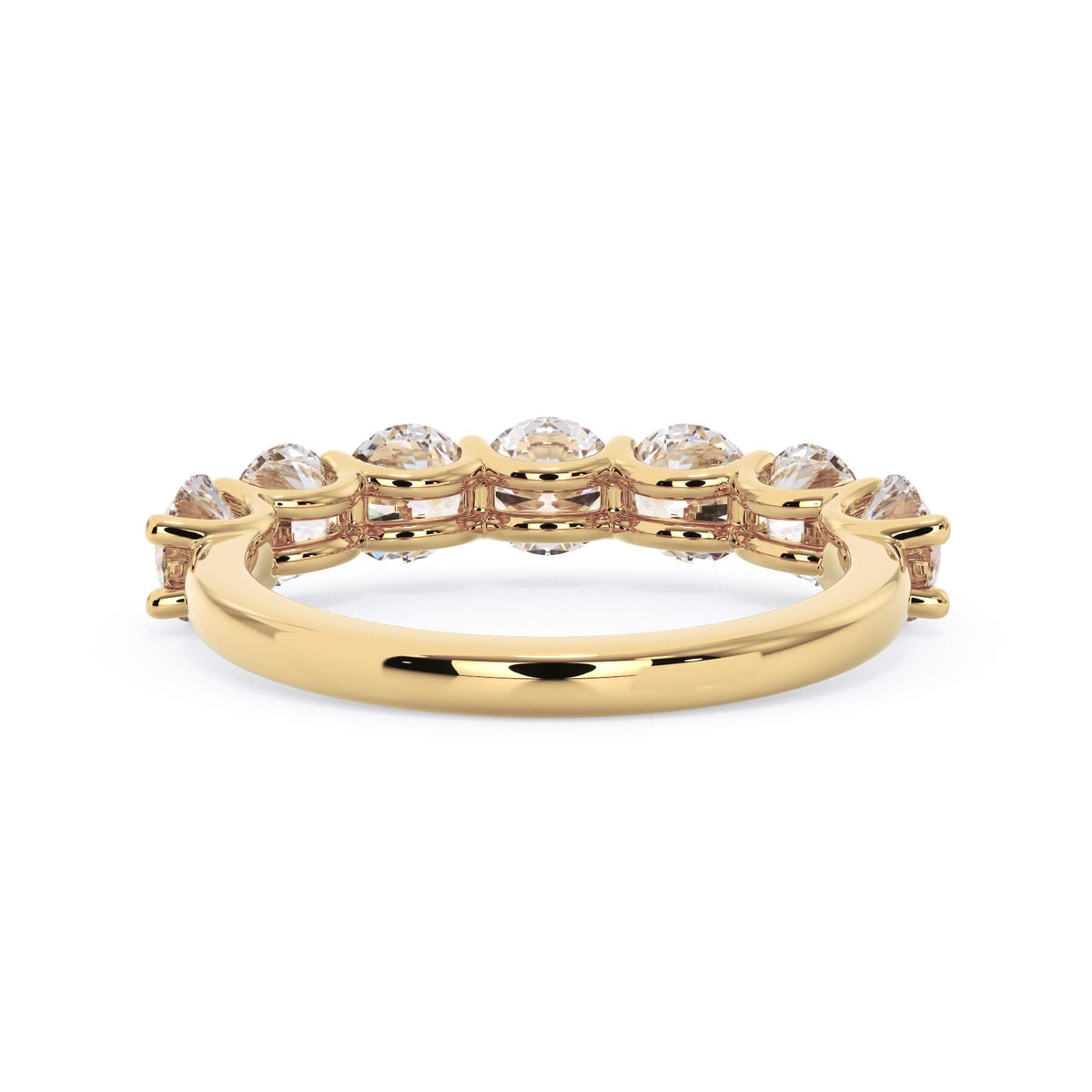 A picture of a seven stone diamond wedding ring with round diamonds that are U prong set in yellow gold on a white background with a view of the underside of the ring.