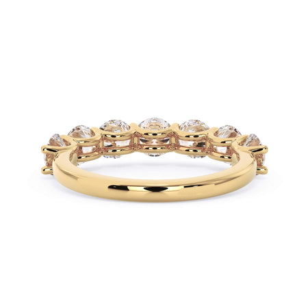 A picture of a seven stone diamond wedding ring with round diamonds that are U prong set in yellow gold on a white background with a view of the underside of the ring.
