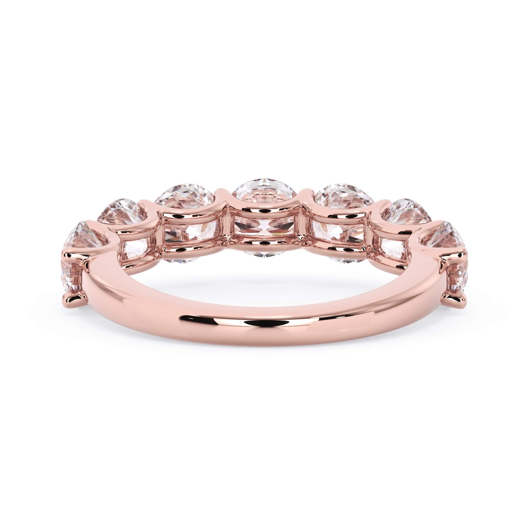 A picture of a seven stone diamond wedding ring with round diamonds that are U prong set in rose gold on a white background with a view of the underside of the ring.