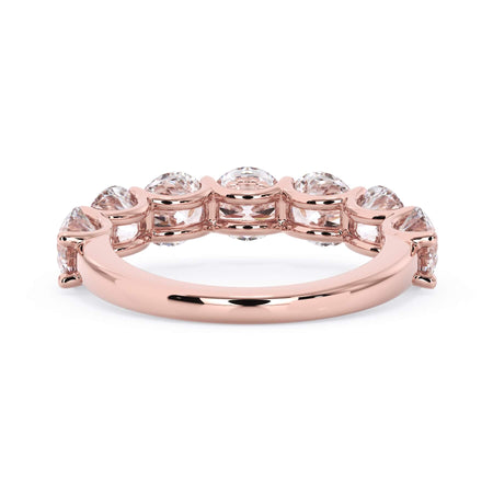 A picture of a seven stone diamond wedding ring with round diamonds that are U prong set in rose gold on a white background with a view of the underside of the ring.