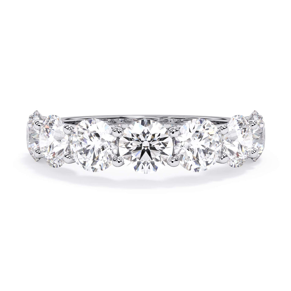 A picture of a seven stone diamond wedding ring with round diamonds that are U prong set in white gold or platinum on a white background with the ring facing forward, lying down.