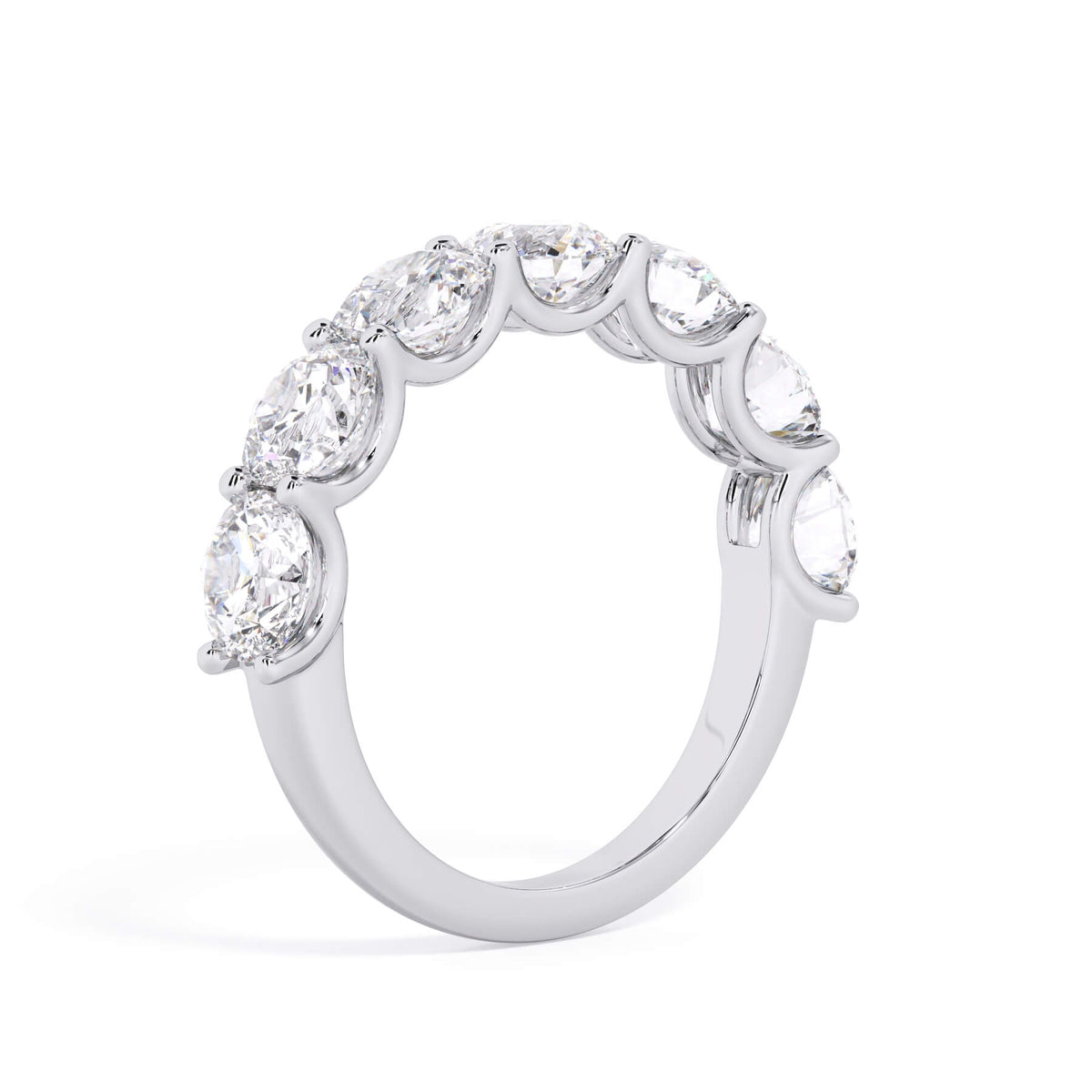 A picture of a seven stone diamond wedding ring with round diamonds that are U prong set in white gold or platinum on a white background with a slightly angled, through the finger view.