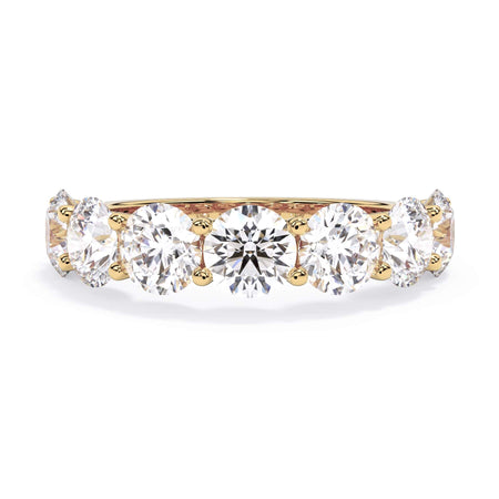 A picture of a seven stone diamond wedding ring with round diamonds that are U prong set in yellow gold on a white background with the ring facing forward, lying down.