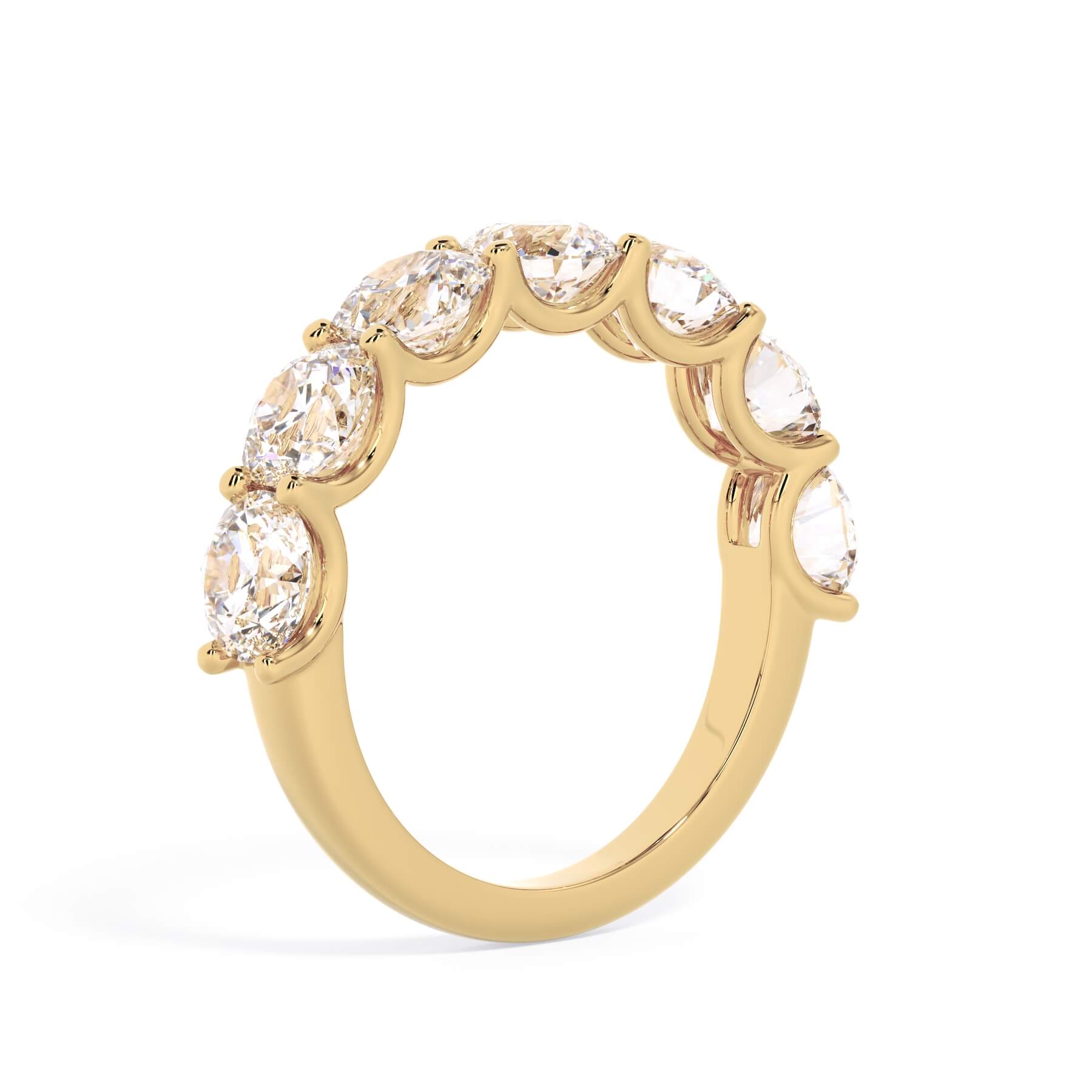 A picture of a seven stone diamond wedding ring with round diamonds that are U prong set in yellow gold on a white background with a slightly angled, through the finger view.