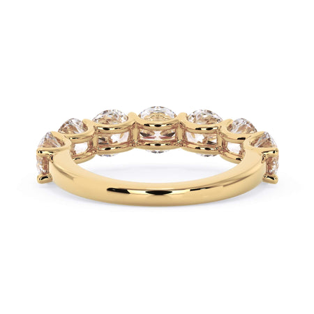 A picture of a seven stone diamond wedding ring with round diamonds that are U prong set in yellow gold on a white background with a view of the underside of the ring.