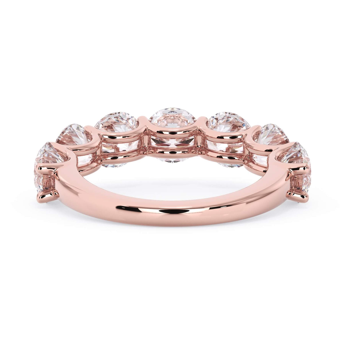 A picture of a seven stone diamond wedding ring with round diamonds that are U prong set in rose gold on a white background with a view of the underside of the ring.