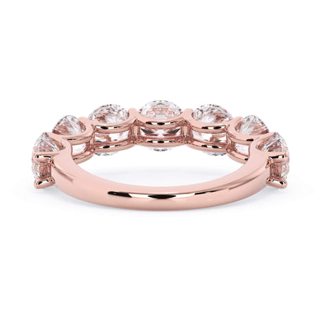 A picture of a seven stone diamond wedding ring with round diamonds that are U prong set in rose gold on a white background with a view of the underside of the ring.