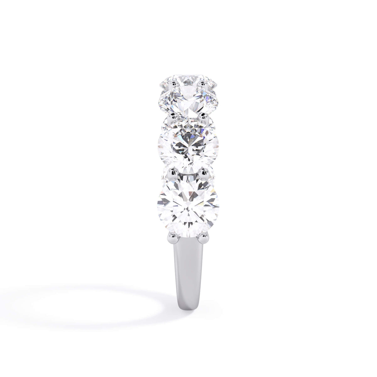 A picture of a seven stone diamond wedding ring with round diamonds that are U prong set in white gold or platinum on a white background with a side profile view.
