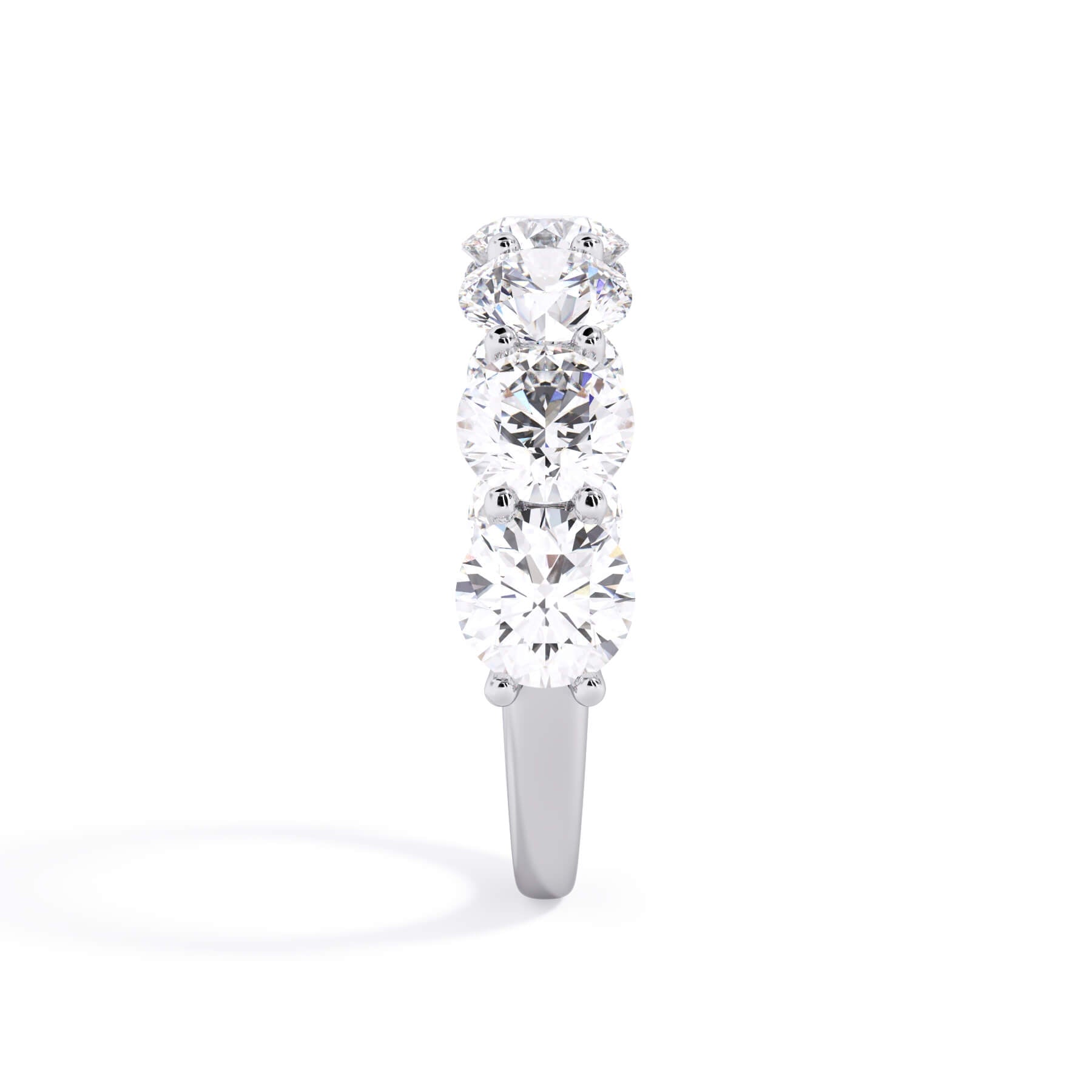 A picture of a seven stone diamond wedding ring with round diamonds that are U prong set in white gold or platinum on a white background with a side profile view.