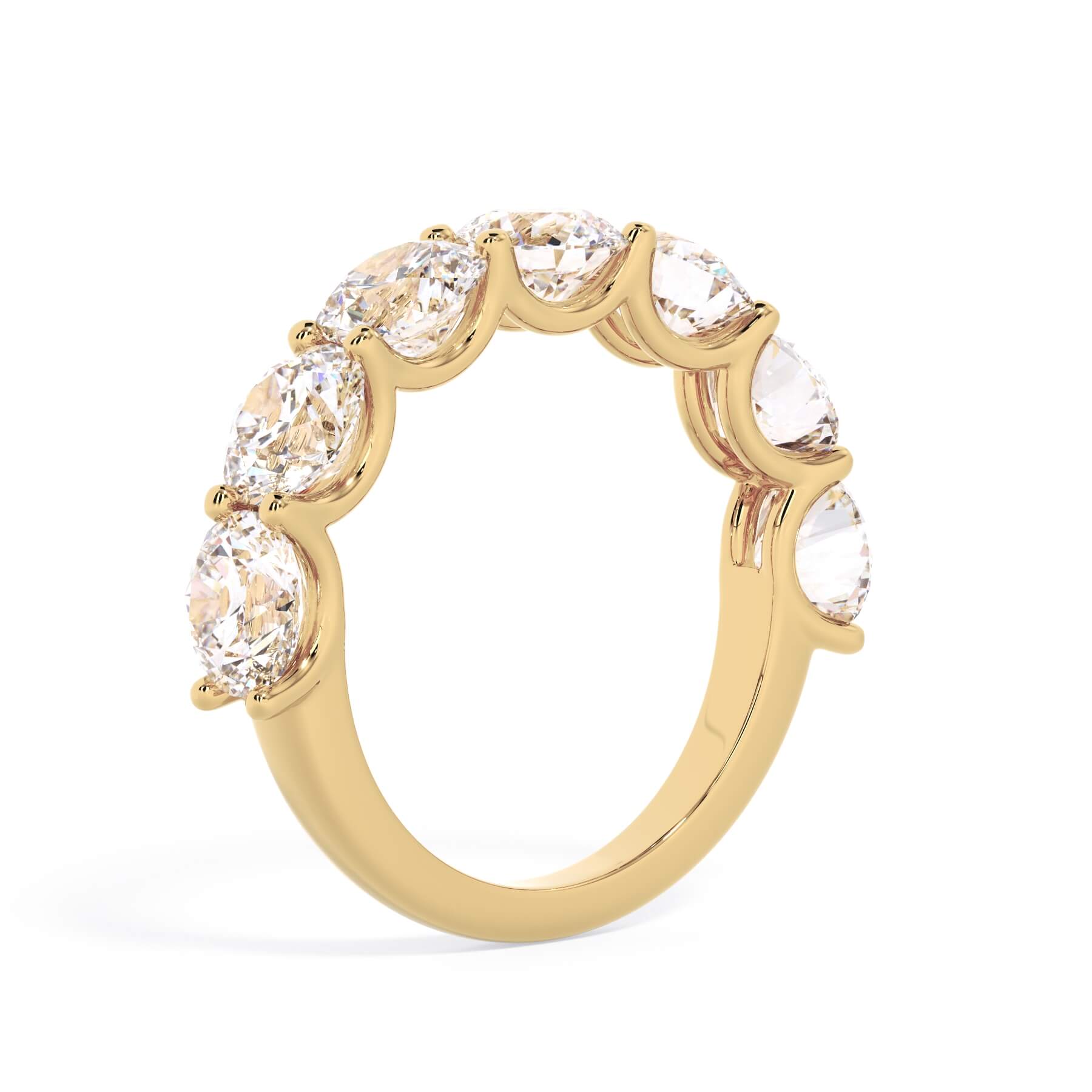 A picture of a seven stone diamond wedding ring with round diamonds that are U prong set in yellow gold on a white background with a slightly angled, through the finger view.