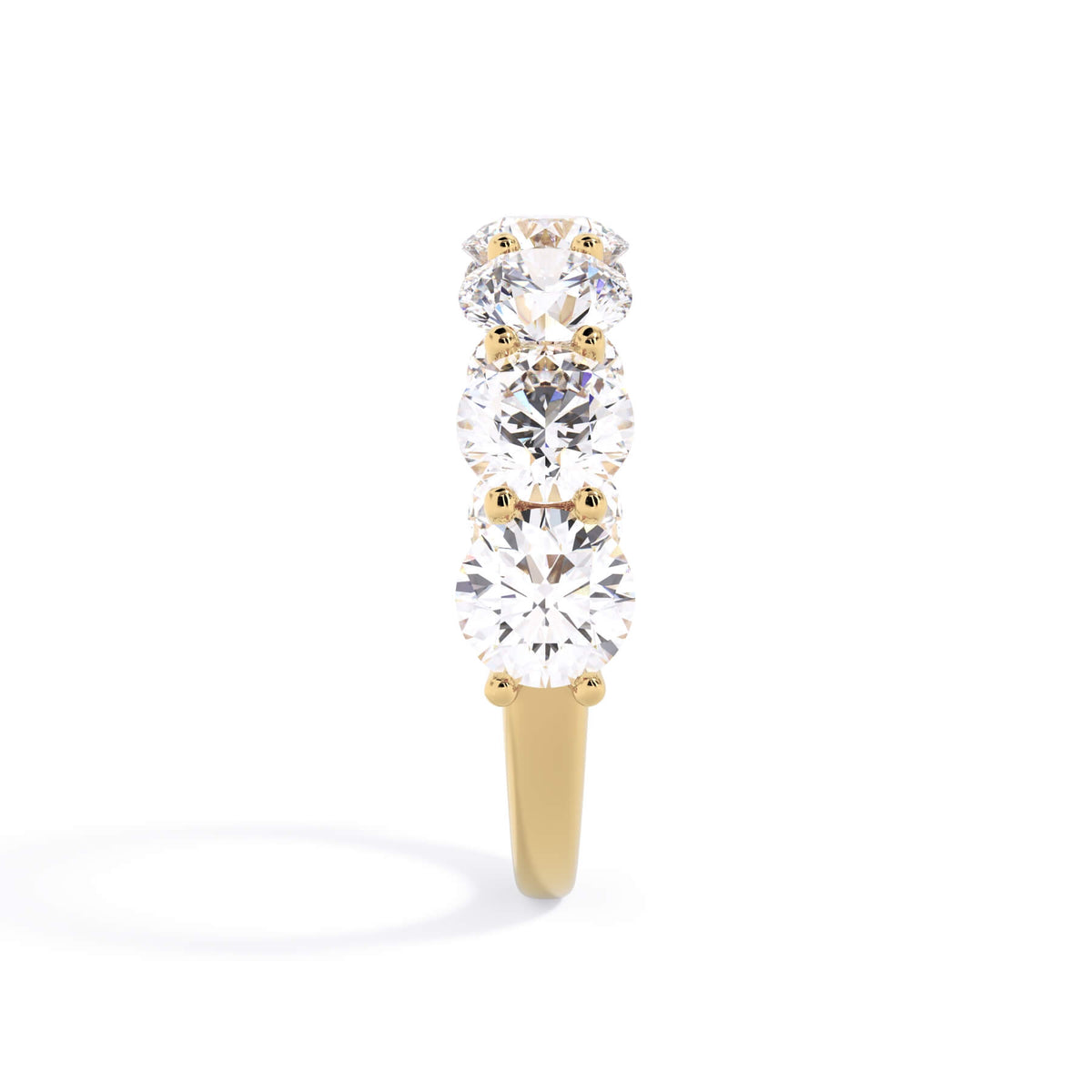 A picture of a seven stone diamond wedding ring with round diamonds that are U prong set in yellow gold on a white background with a side profile view.