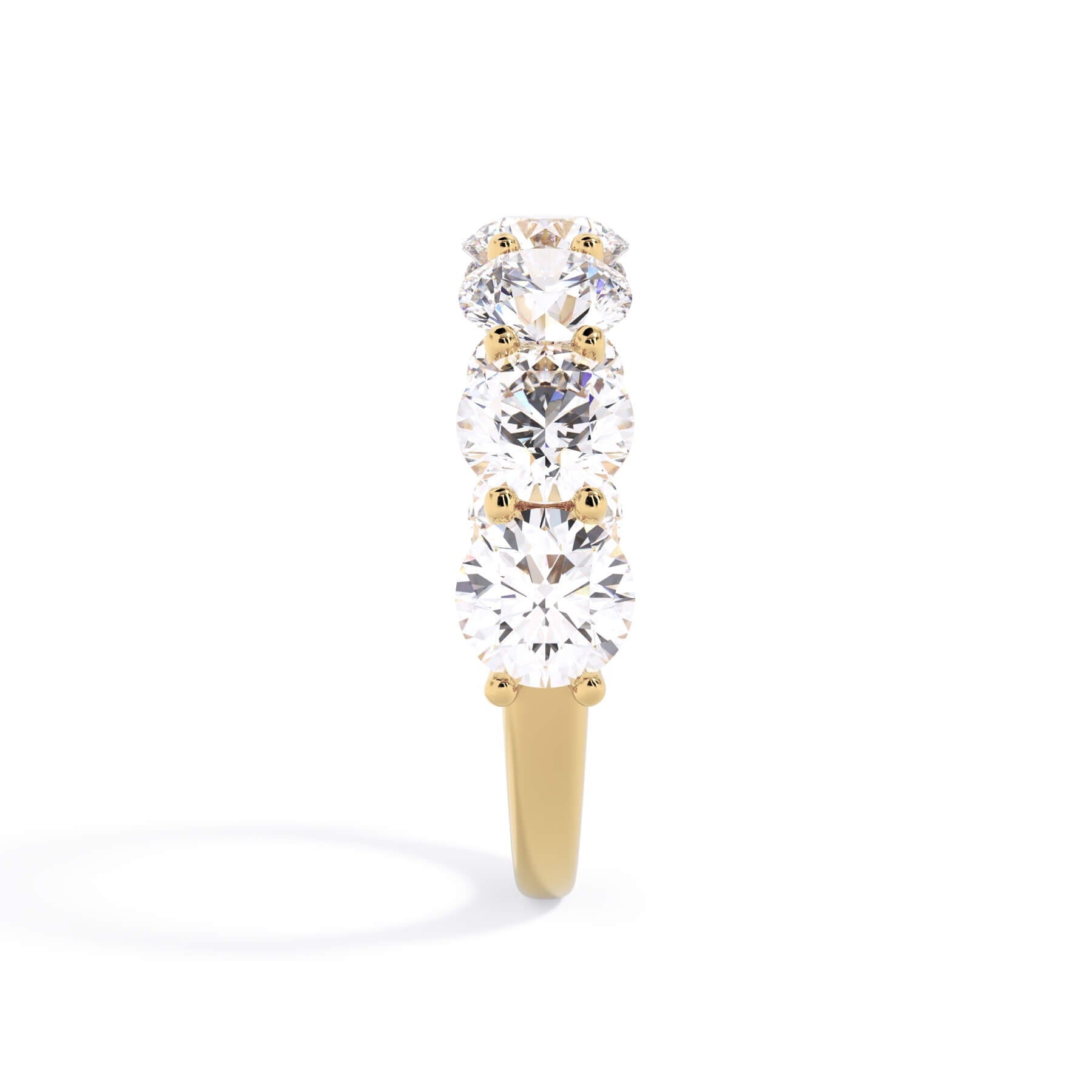 A picture of a seven stone diamond wedding ring with round diamonds that are U prong set in yellow gold on a white background with a side profile view.