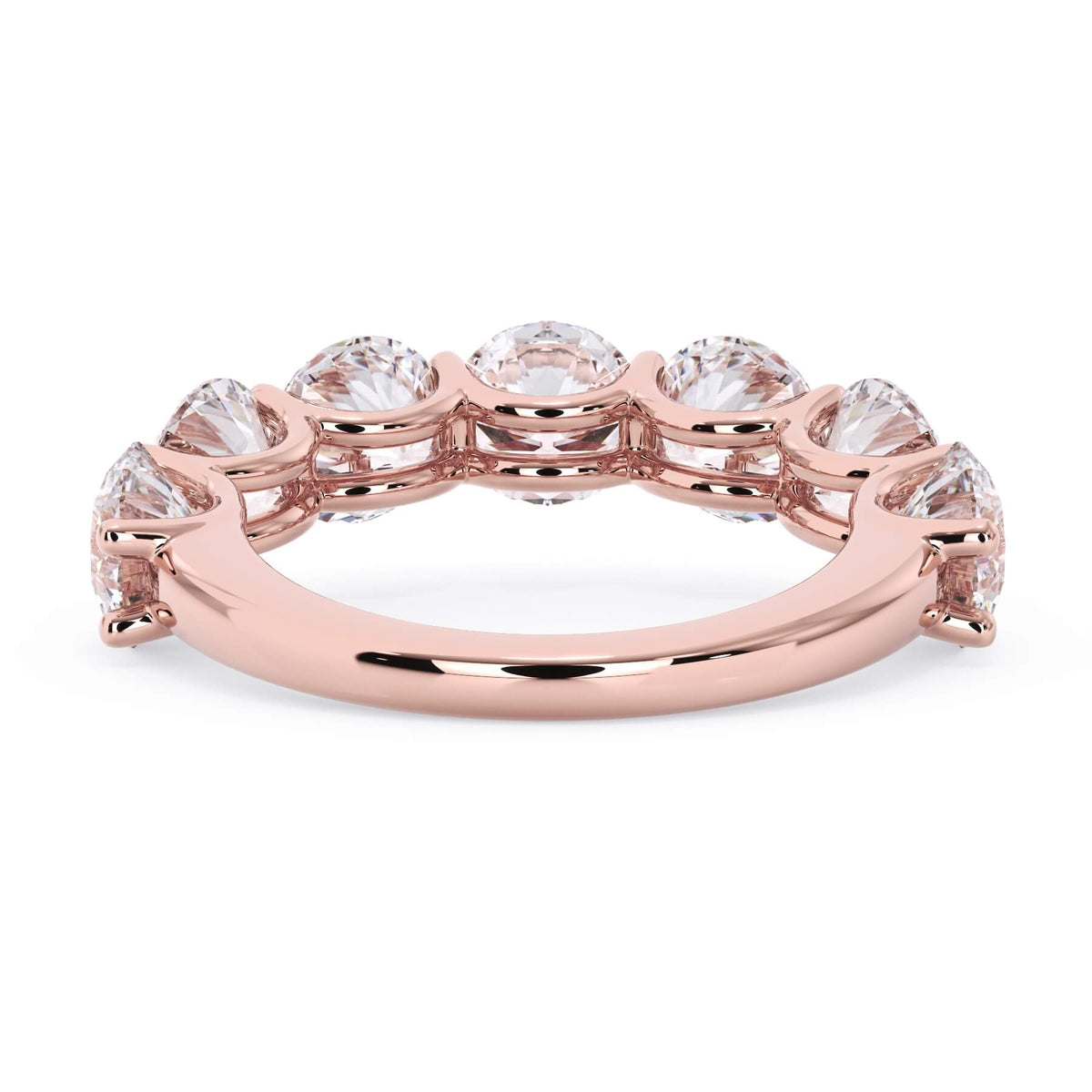 A picture of a seven stone diamond wedding ring with round diamonds that are U prong set in rose gold on a white background with a view of the underside of the ring.