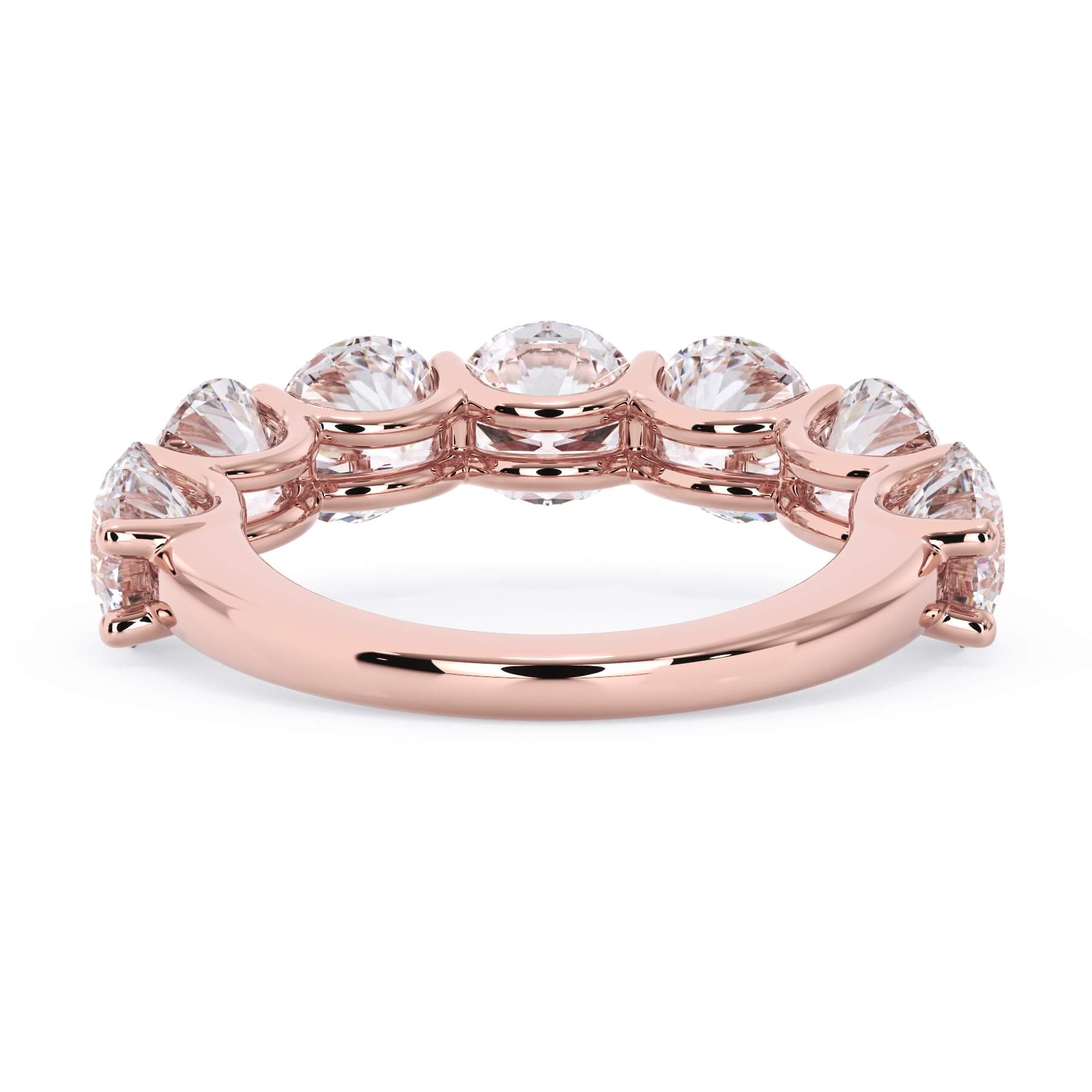 A picture of a seven stone diamond wedding ring with round diamonds that are U prong set in rose gold on a white background with a view of the underside of the ring.