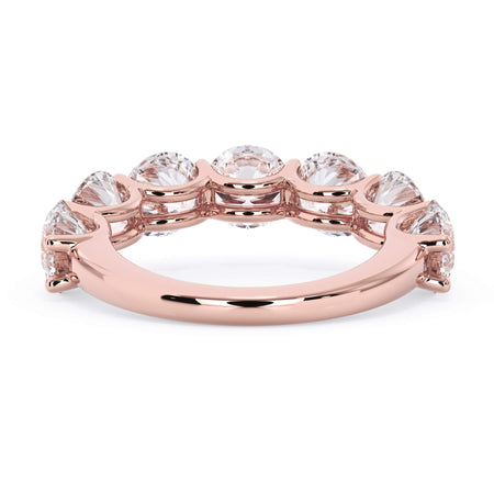 A picture of a seven stone diamond wedding ring with round diamonds that are U prong set in rose gold on a white background with a view of the underside of the ring.