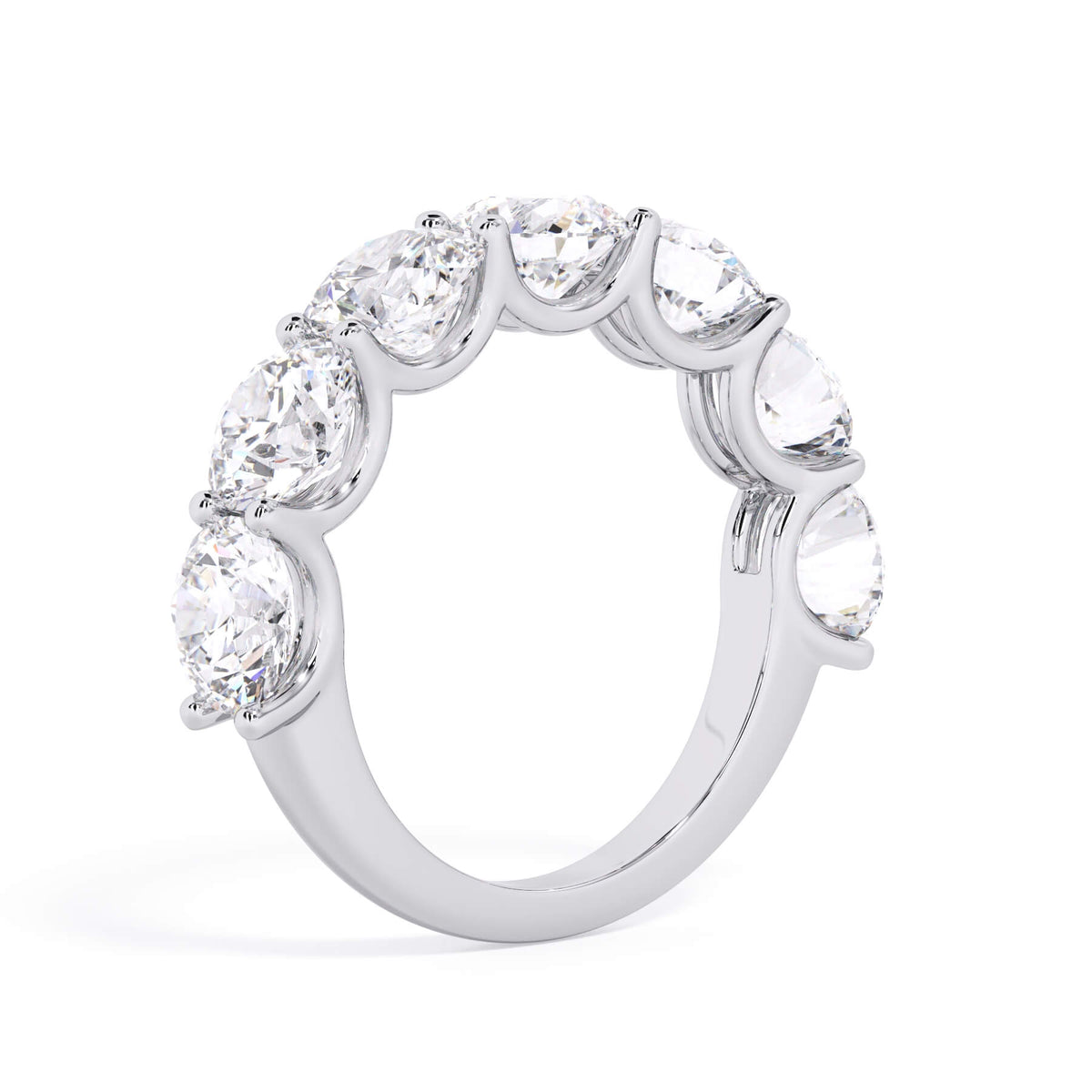 A picture of a seven stone diamond wedding ring with round diamonds that are U prong set in white gold or platinum on a white background with a slightly angled, through the finger view.