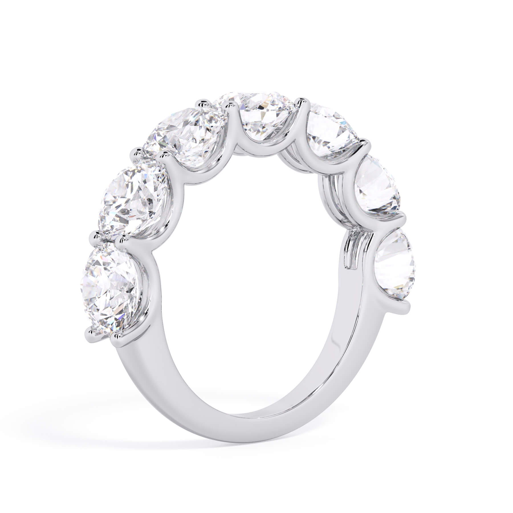 A picture of a seven stone diamond wedding ring with round diamonds that are U prong set in white gold or platinum on a white background with a slightly angled, through the finger view.