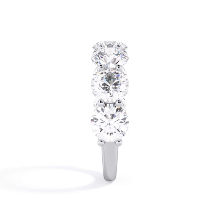 A picture of a seven stone diamond wedding ring with round diamonds that are U prong set in white gold or platinum on a white background with a side profile view.