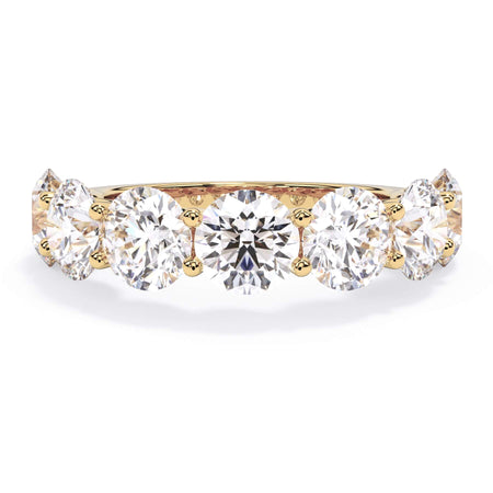 A picture of a seven stone diamond wedding ring with round diamonds that are U prong set in yellow gold on a white background with the ring facing forward, lying down.