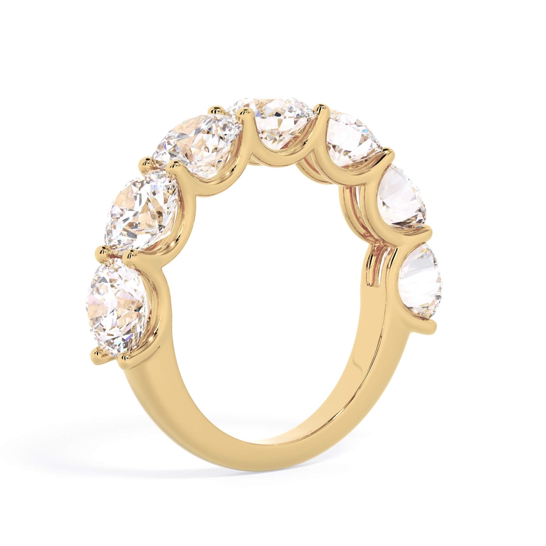 A picture of a seven stone diamond wedding ring with round diamonds that are U prong set in yellow gold on a white background with a slightly angled, through the finger view.