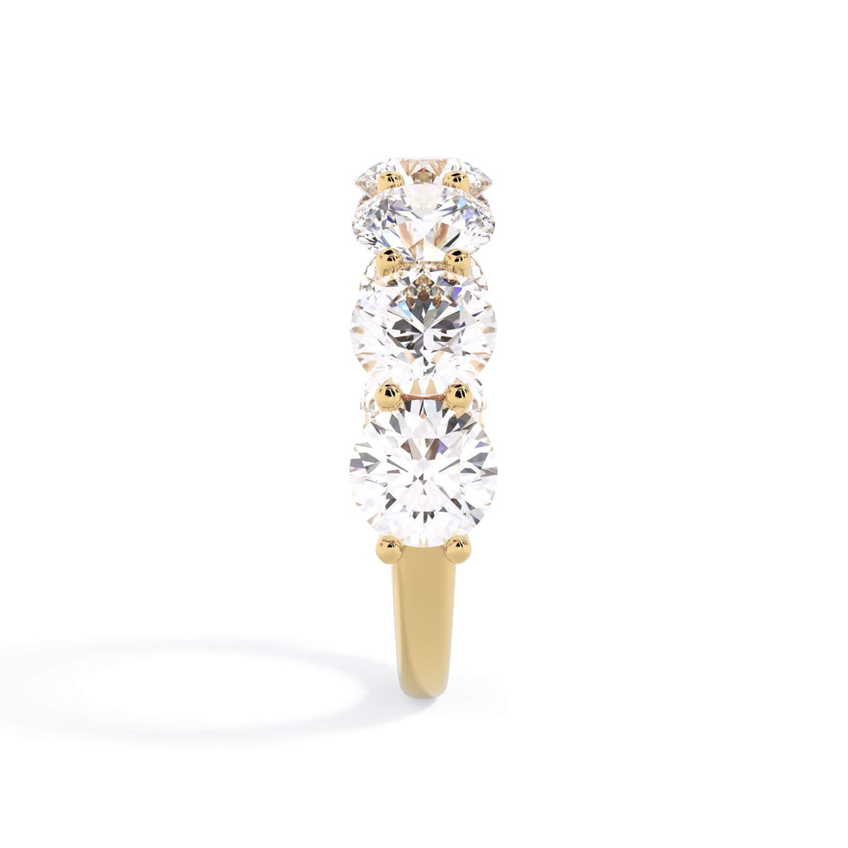 A picture of a seven stone diamond wedding ring with round diamonds that are U prong set in yellow gold on a white background with a side profile view.