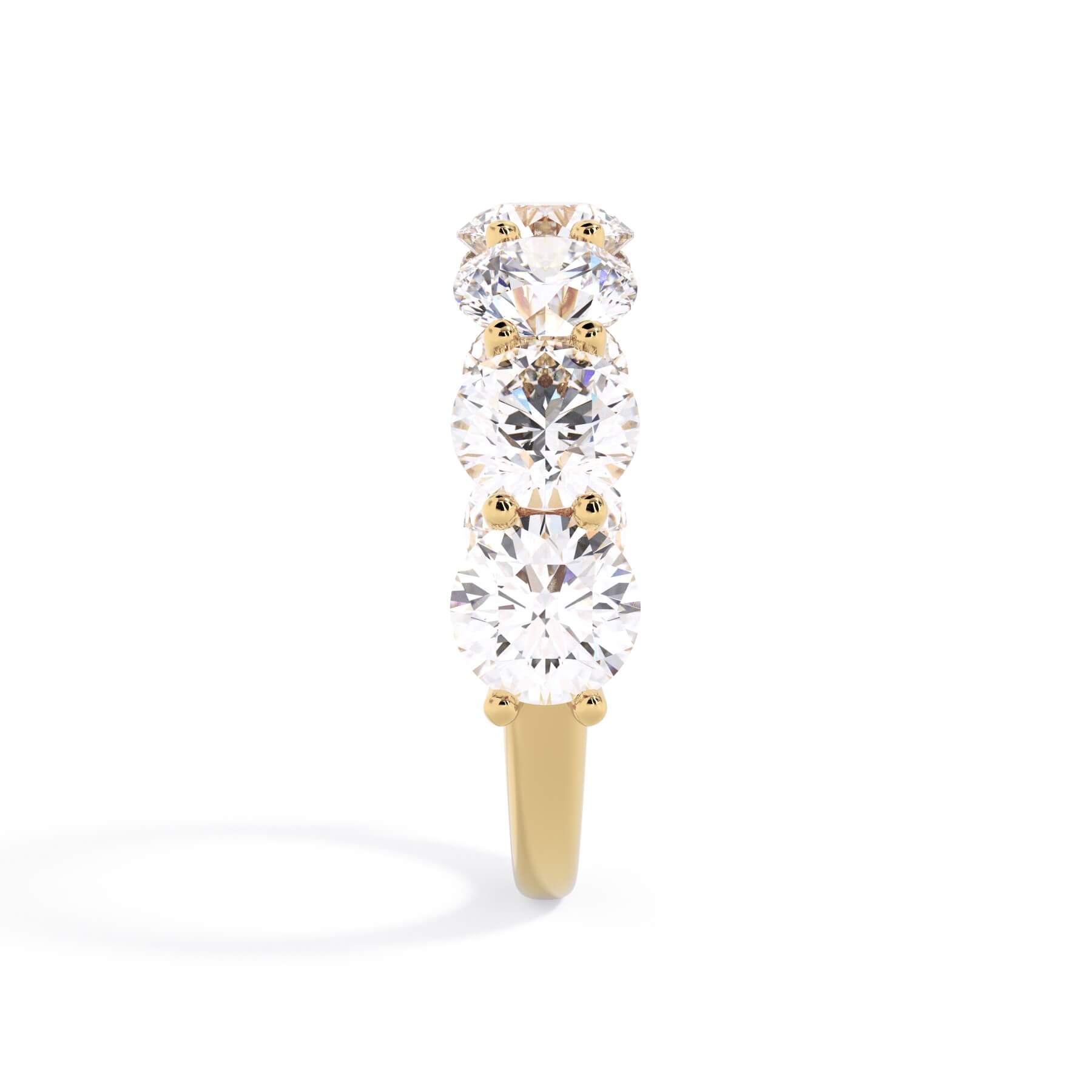 A picture of a seven stone diamond wedding ring with round diamonds that are U prong set in yellow gold on a white background with a side profile view.
