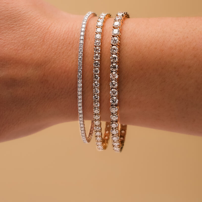Three Diamond Tennis Bracelets on a woman's wrist.